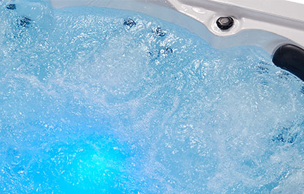 Bubbling spa water lit from beneath with blue LED lighting against a white porcelain shell